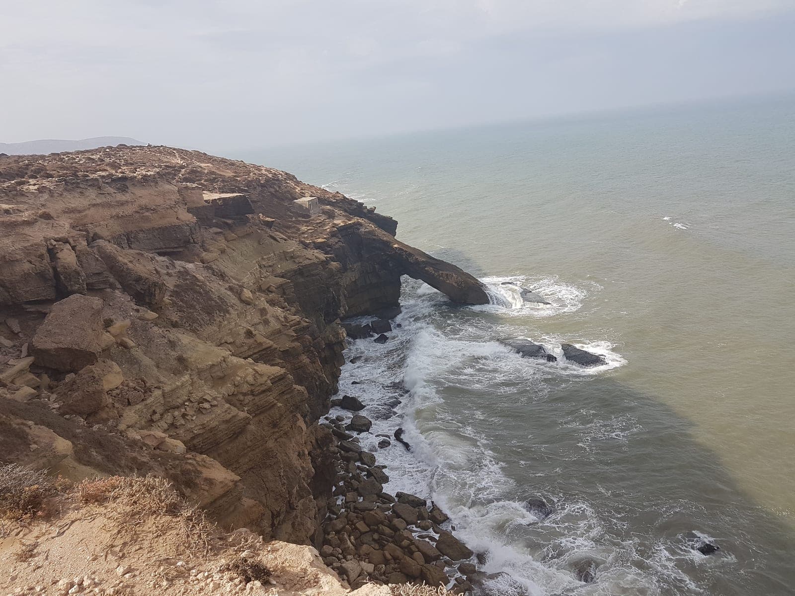 Natural rock arch in the sea cliffs with Atlantic surf breaking below, on the coast of Morocco