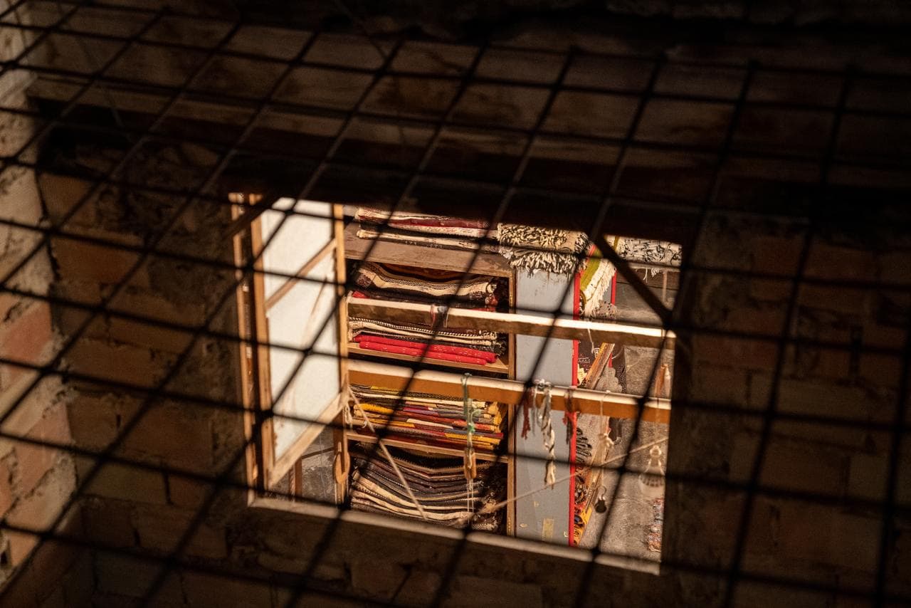 Stacked carpets and textiles seen through an iron window grille in the Fes medina, Morocco