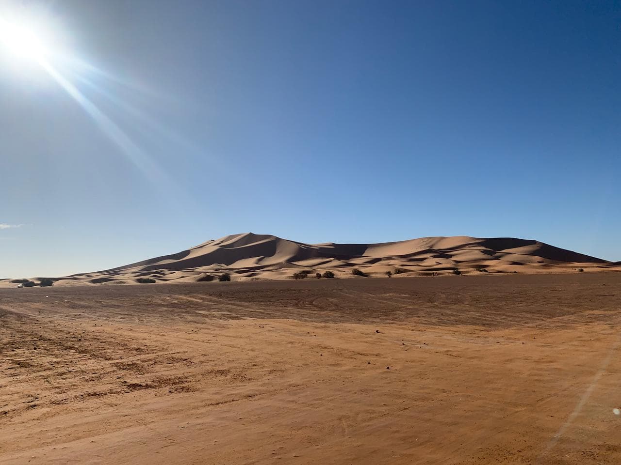 The full ridge of the Erg Chebbi dunes rising off the flat hammada plain outside Merzouga, Morocco