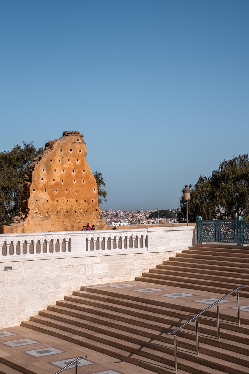The broad stone steps up to the Hassan esplanade with the ruined ochre mosque wall above and Rabat spread out behind, Morocco