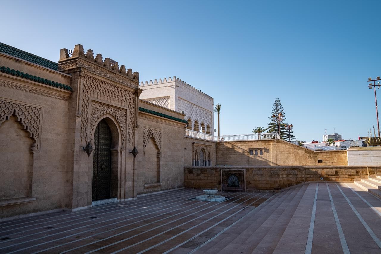 Carved stucco portal and bronze door of the Mausoleum of Mohammed V beneath its green tiled roofline, Rabat Morocco
