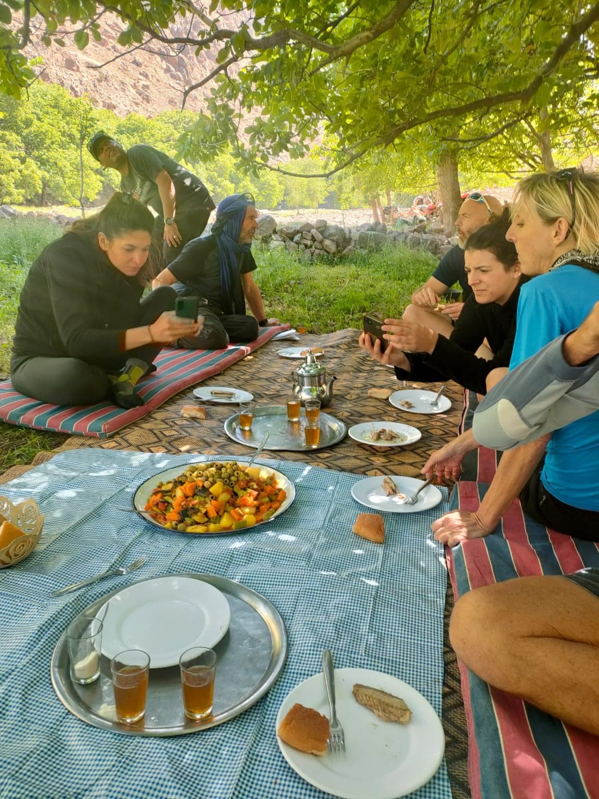 Trailside lunch of Berber salad and mint tea spread on rugs under walnut trees, High Atlas Morocco