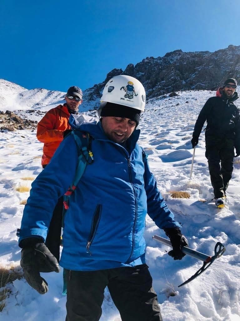 A trekker in helmet and crampons on a winter ascent in the snow-covered High Atlas, Morocco